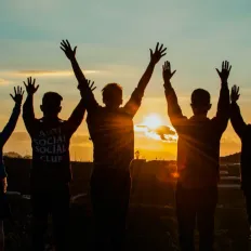 Mensen die juichen bij zonsondergang
