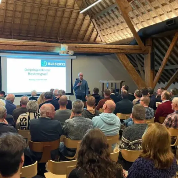 Bewoners in een zaal voor een informatiebijeenkomst